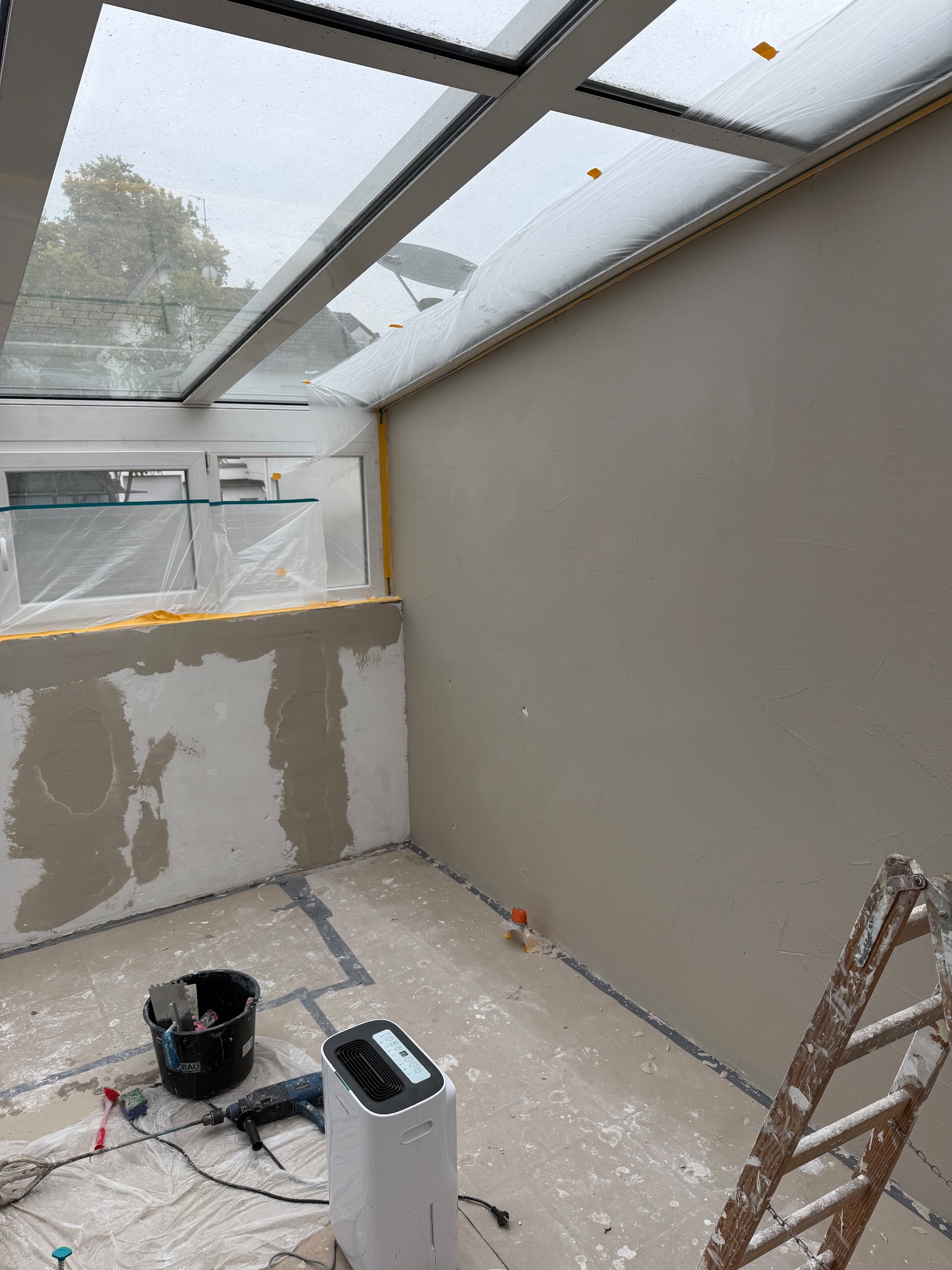 Wintergarten in der Renovierung mit verputzten Wänden und Schutzfolie