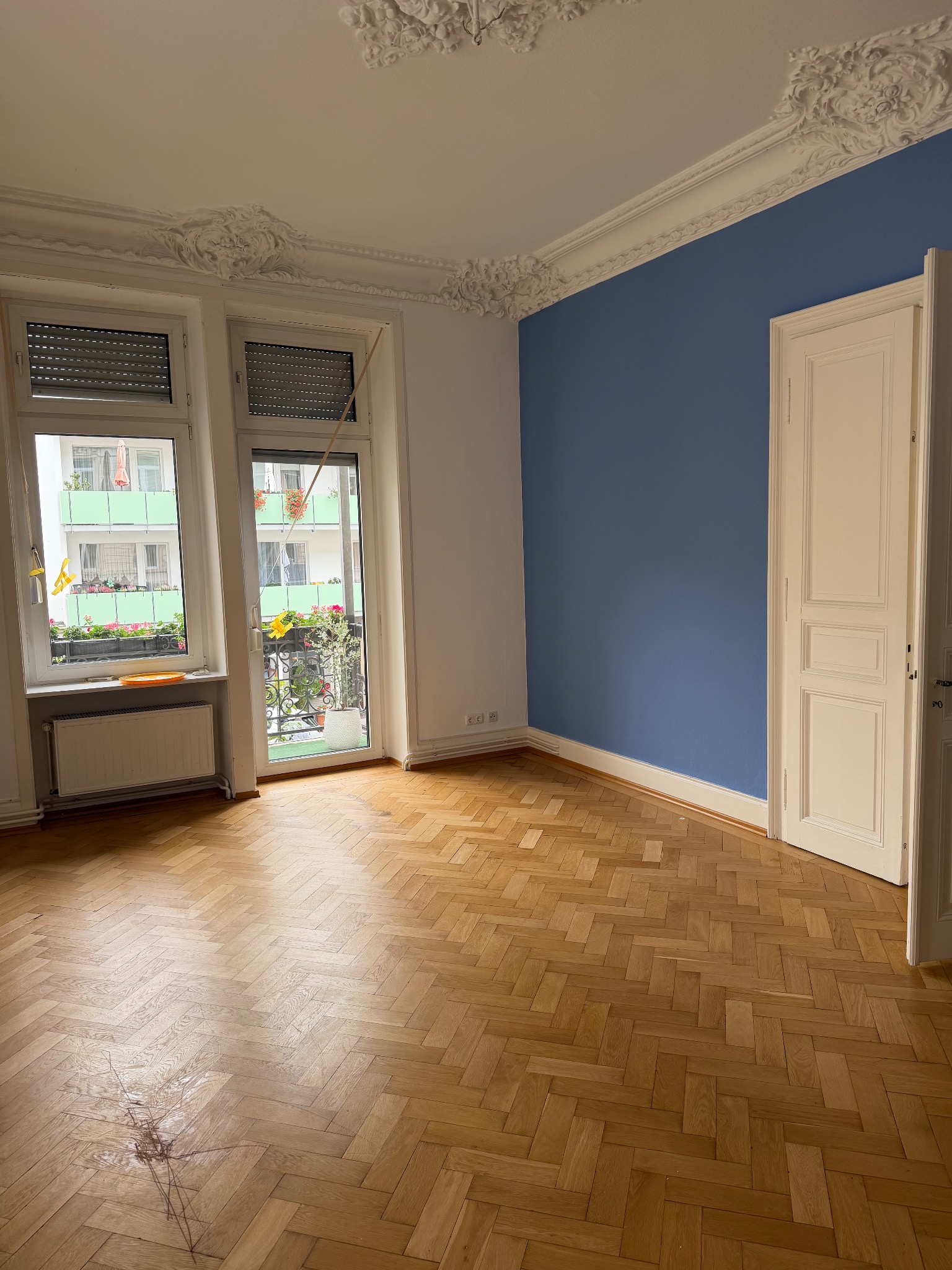 Großzügiger Raum mit blauer Wand und Fischgrät-Parkett