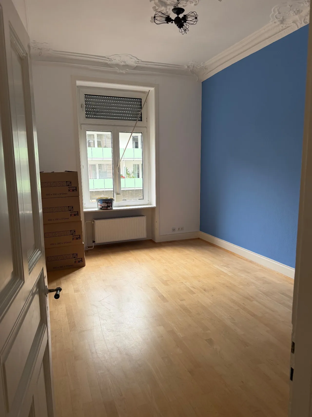 Renovierter Raum mit blauer Akzentwand und aufgearbeitetem Parkett